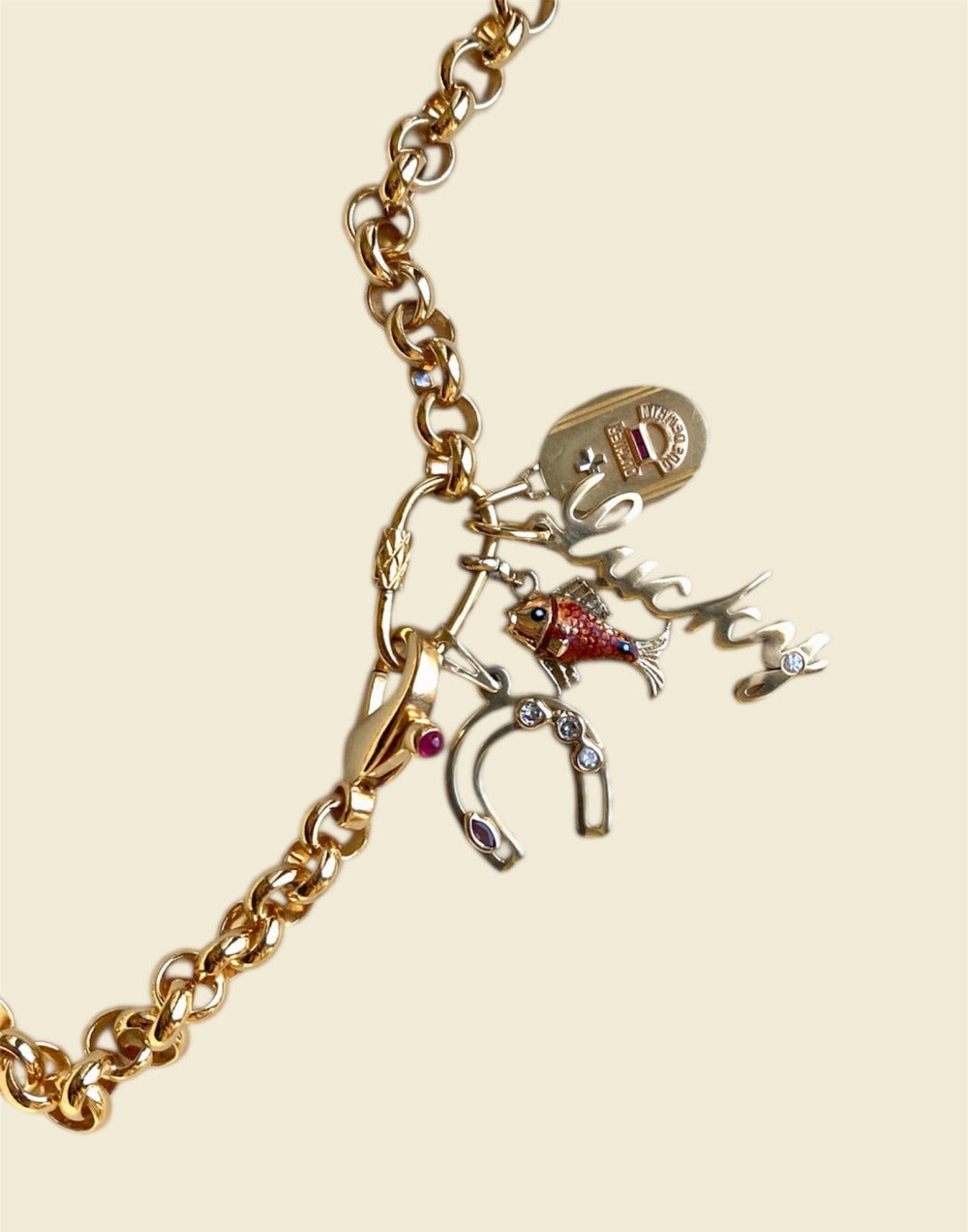 Gold chunky chain necklace with vintage style charms with gemstones on a beige background